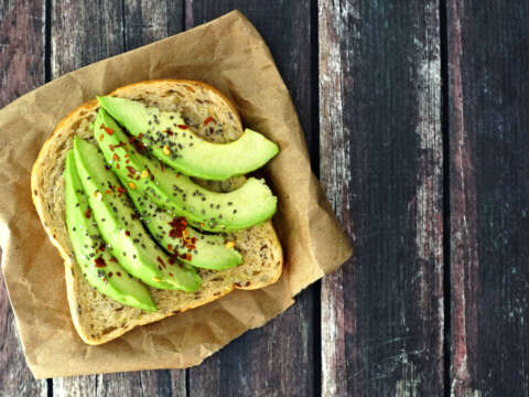 Open avocado sandwich on paper against rustic wood 506815964 1258x838